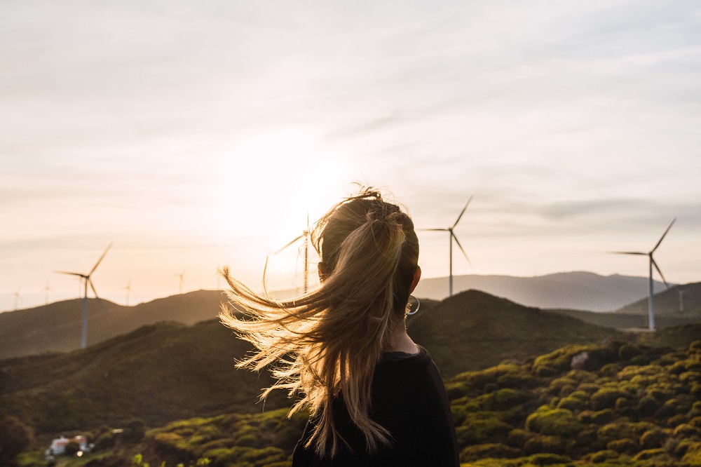 Frau schaut auf Windräder am Horizont